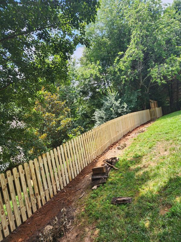 Spaced picket fence along a wooded slope