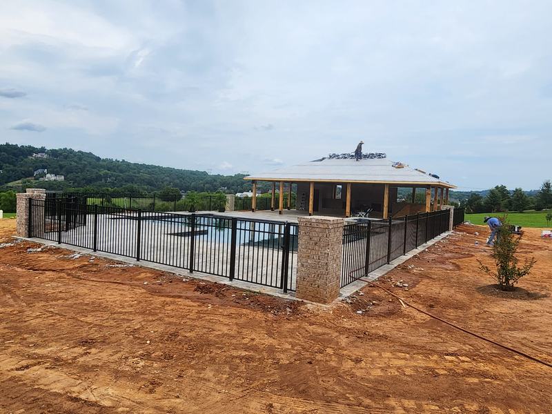 Black aluminum pool fence with brick columns around a new pool