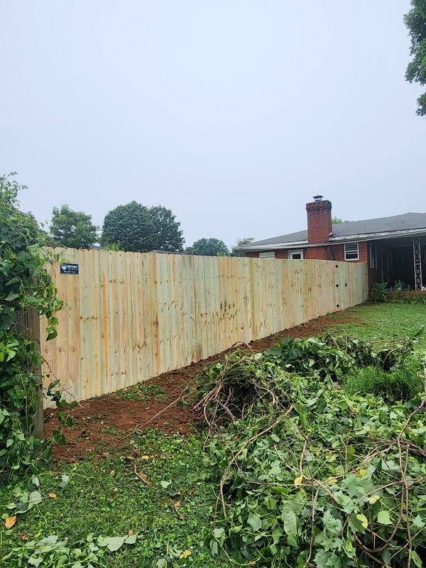 New privacy fence with overgrown brush cleared from the fence line
