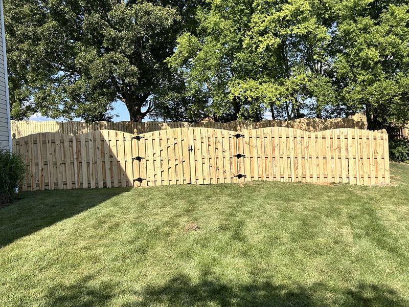 Wood shadowbox privacy fence with a built-in gate across a backyard