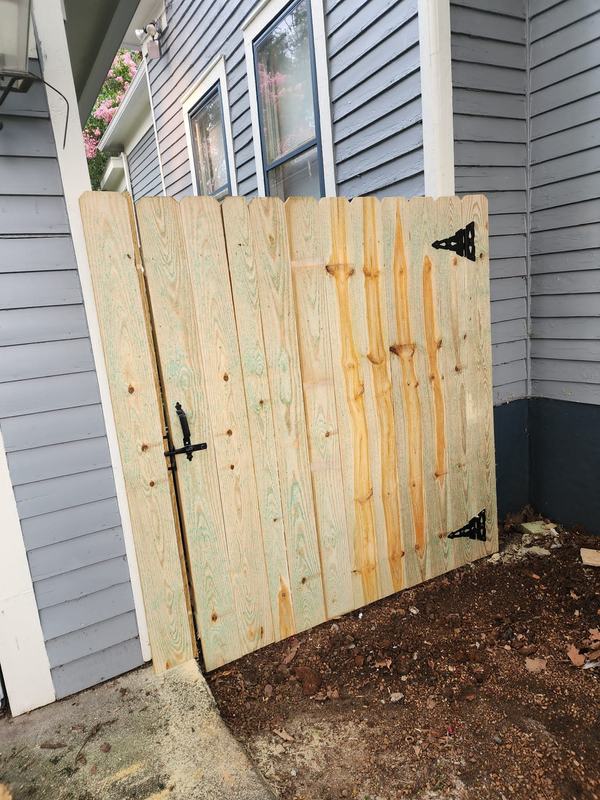 Wood side gate with black hinges and latch beside a house